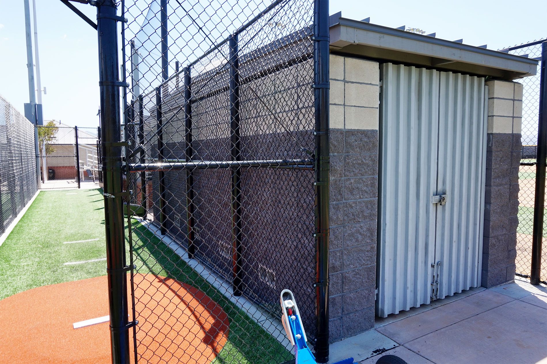 Equipment shed and chain-link enclosure alongside the outfield at the Triunfo YMCA fields