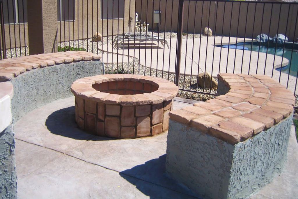 Round stone fire pit with a curved seating wall on a poolside patio