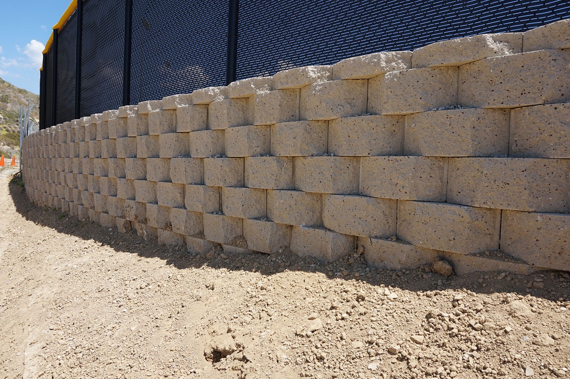 Curved tan segmental block retaining wall running along an outfield boundary
