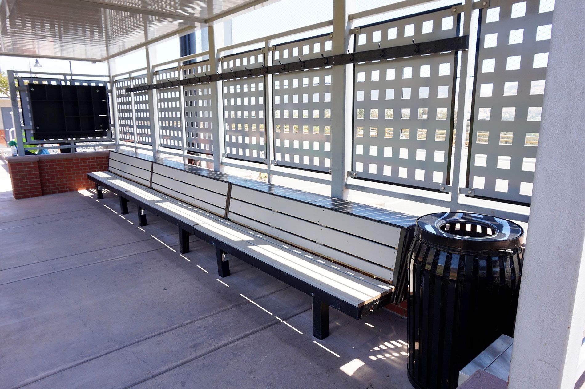 Front of the completed dugout with bench seating behind a perforated steel screen