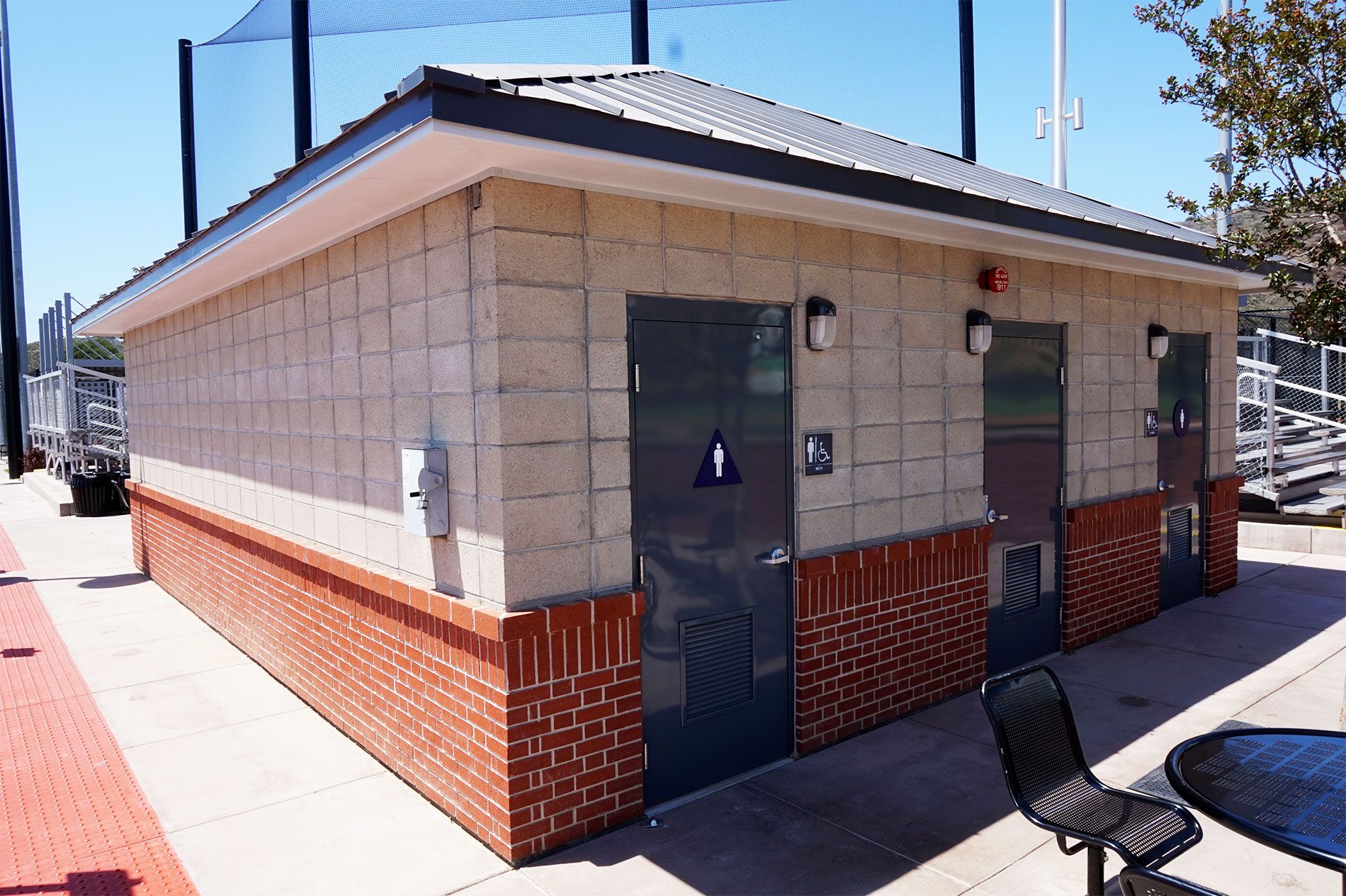 Restroom building at the Triunfo YMCA baseball fields, built in split-face block over a red brick wainscot under a standing-seam roof