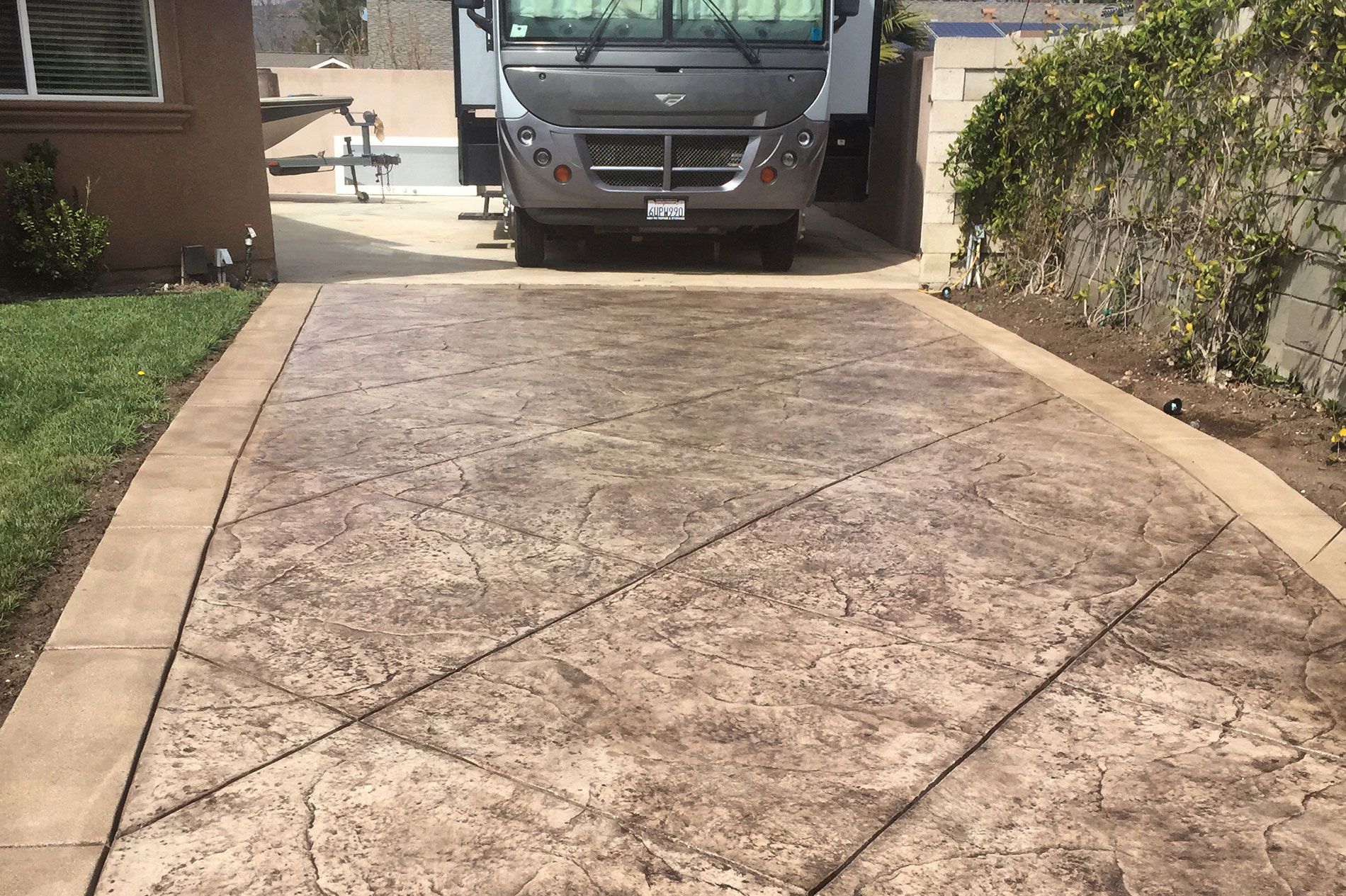 Tan stamped concrete driveway with a scored border running up to a residential garage