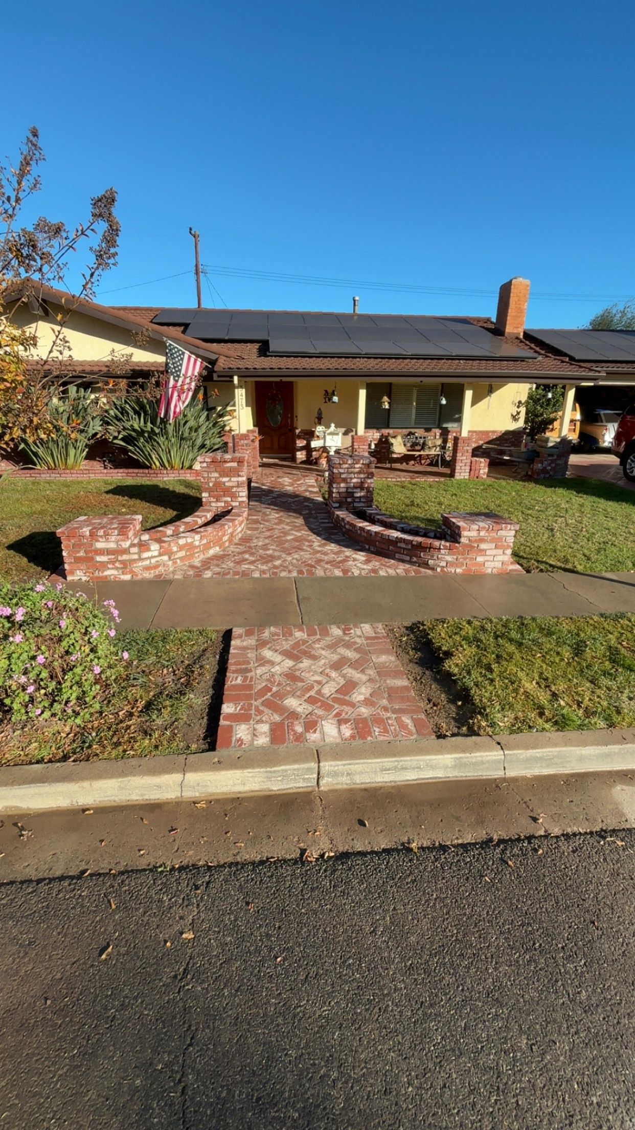 Brick entry walkway laid in herringbone between curved brick planter walls