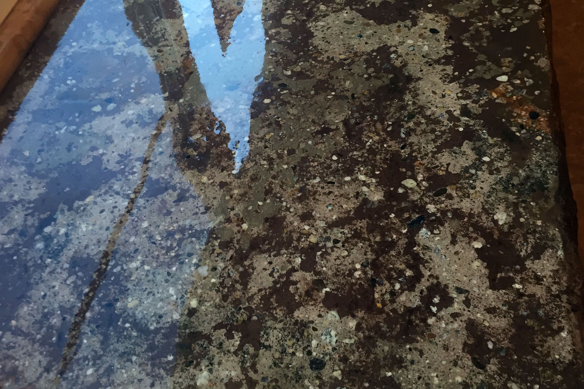 Close on a concrete top polished to a wet look, the aggregate showing through the surface