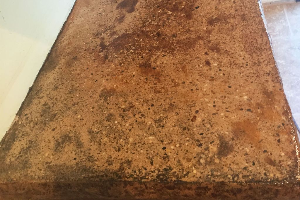 Corner of a concrete kitchen counter in an amber stain, fine aggregate showing in the finish