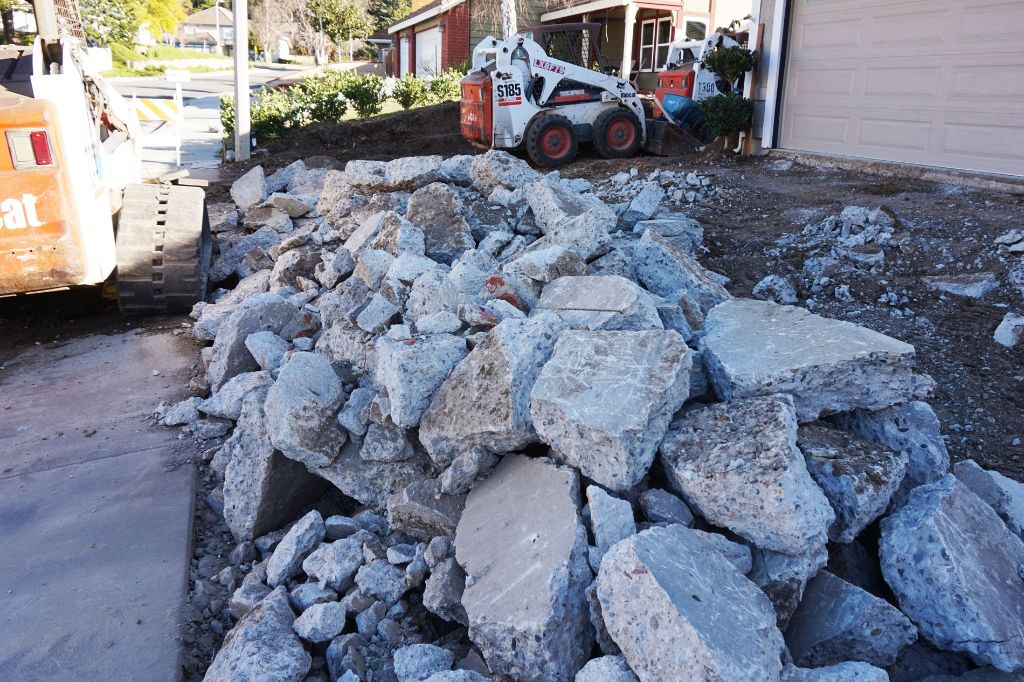 Broken concrete stockpiled beside the loader during driveway demolition