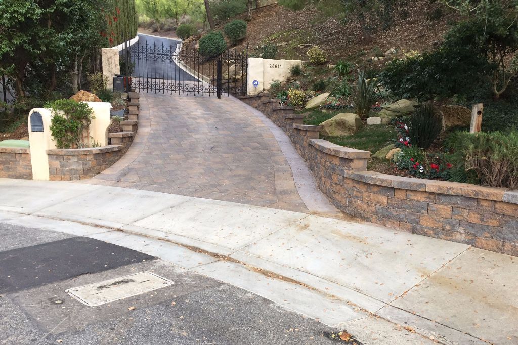 Driveway rising from the street to a gated entry between stone-faced walls, Agoura Hills