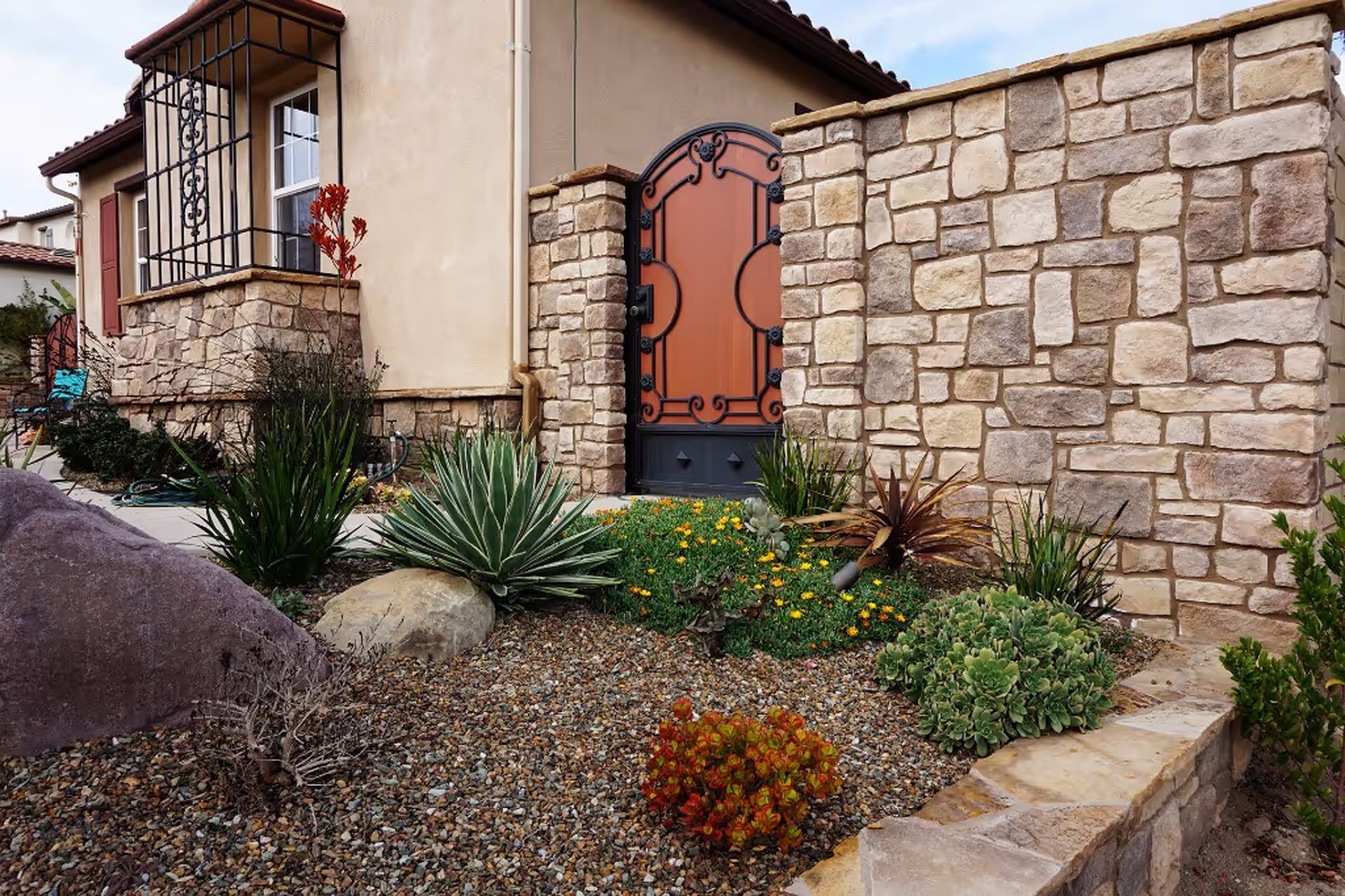 Stone veneer entry columns flanking a walkway with mature foundation planting