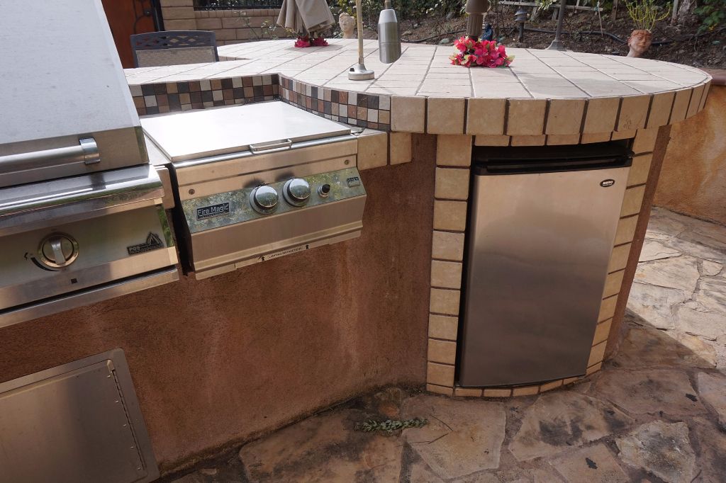 Fire Magic gas barbecue and built-in refrigerated storage set into the tiled outdoor kitchen