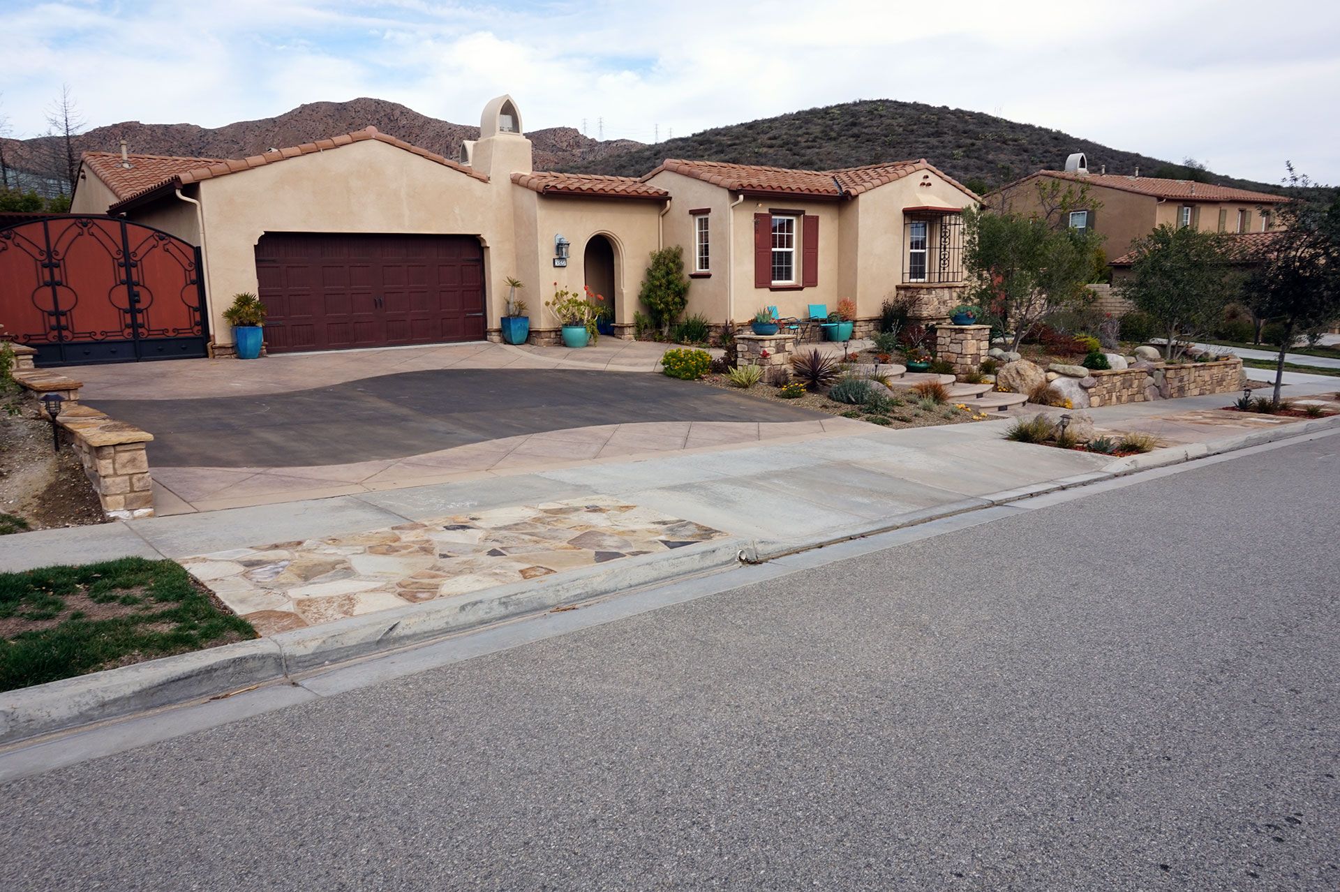 Front elevation of a Dos Vientos house with stone-faced retaining walls and pilasters, a stamped concrete drive and a flagstone apron at the kerb