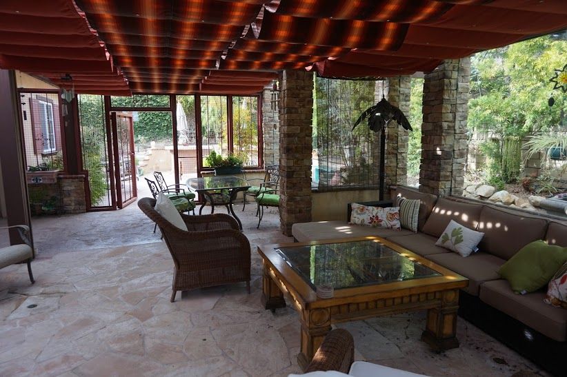 Patio enclosure of stone pillars and retractable awning, opening onto the house through glass doors