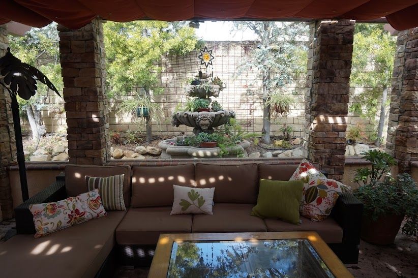 Stone pillars framing a tiered fountain, with built-in sectional seating beneath the awning