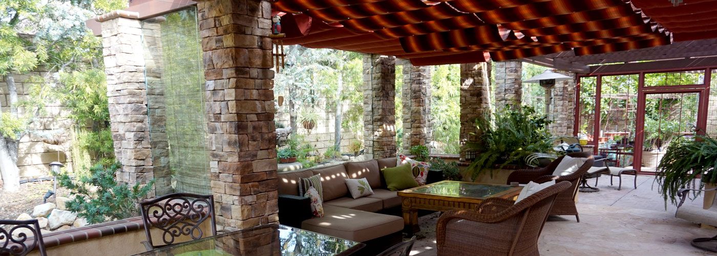 Covered patio with stone columns and a red awning over outdoor furniture