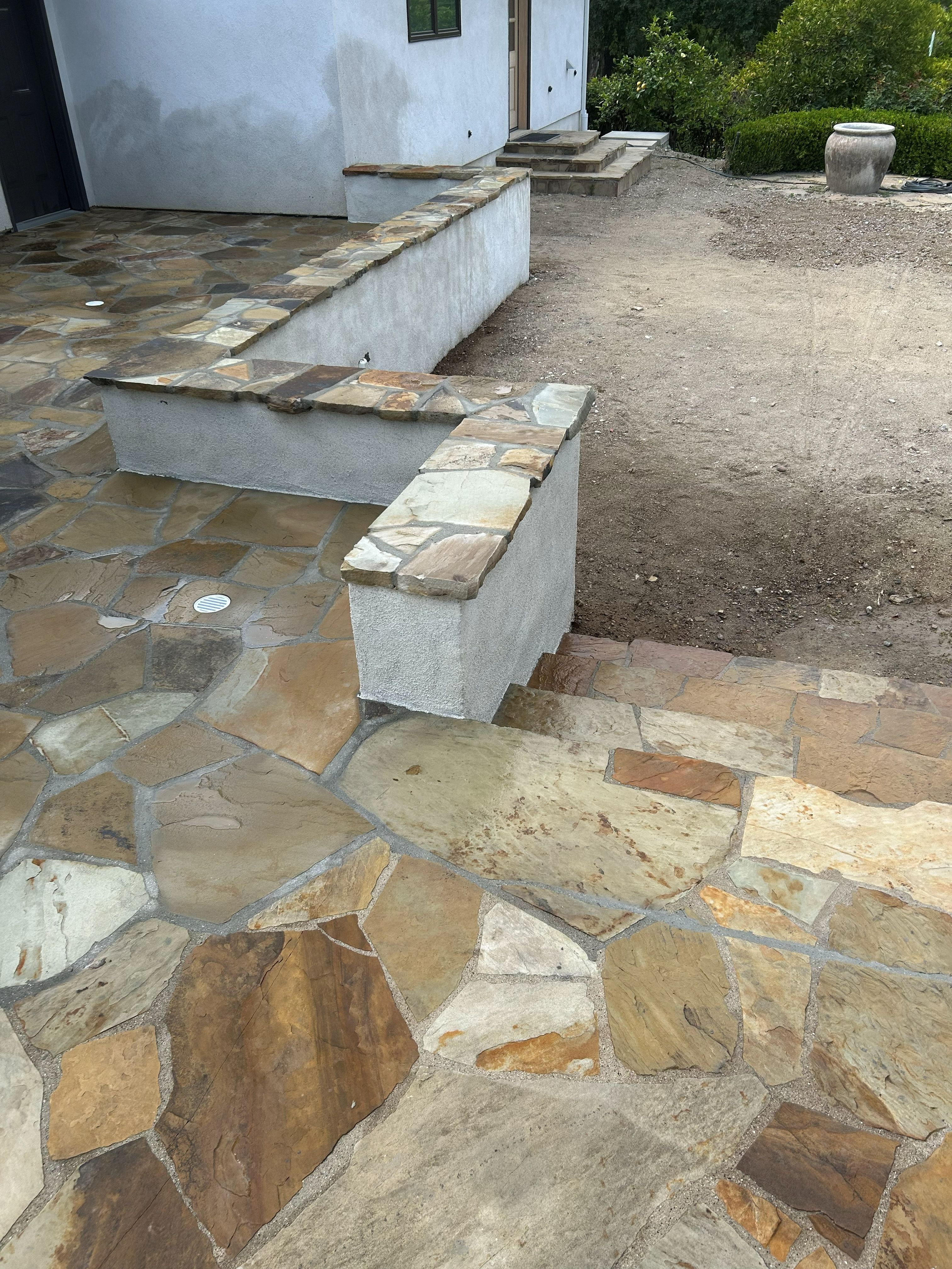 Seat wall rendered in white and capped with cut flagstone, beside a matching patio