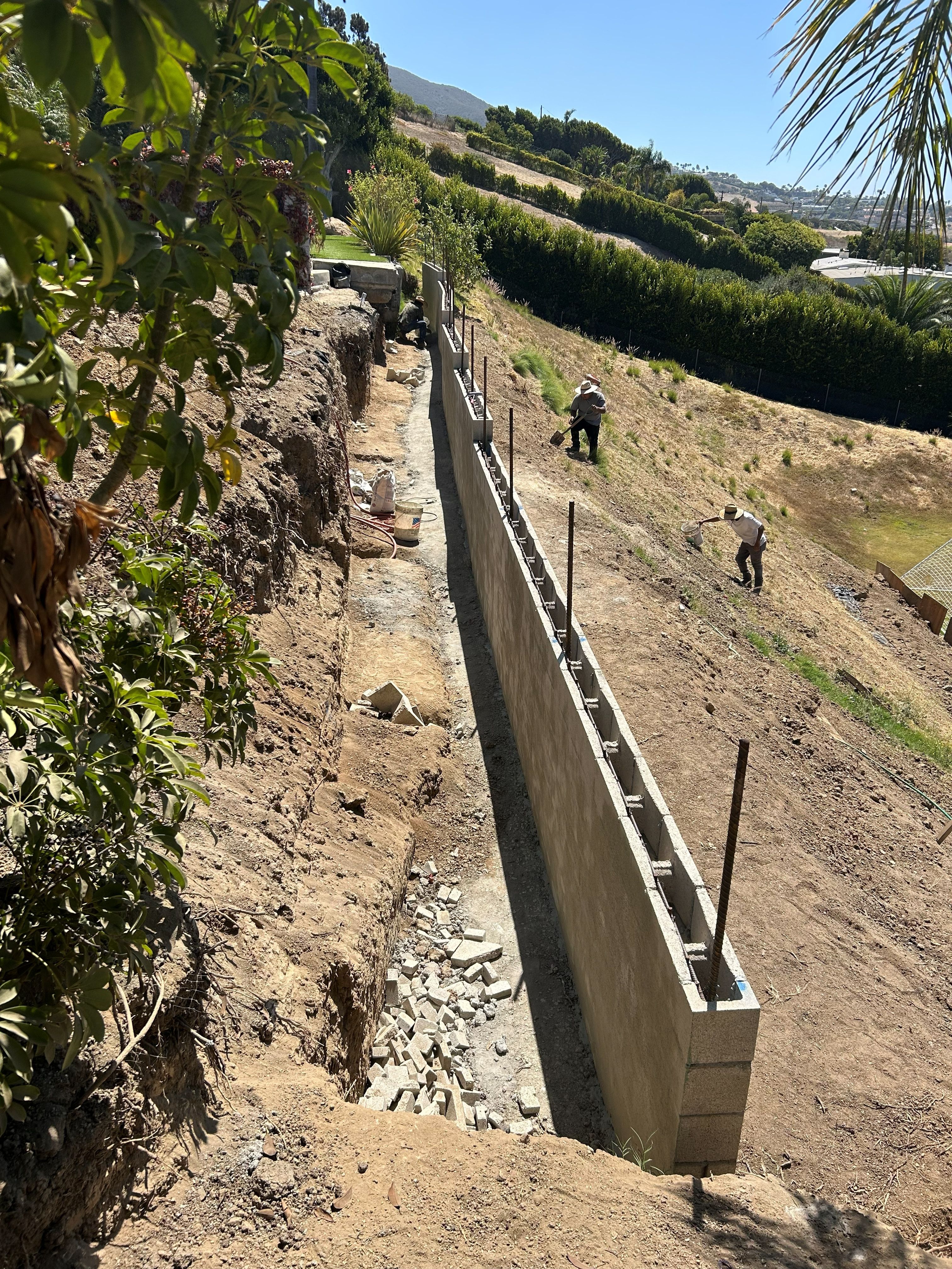 Tall reinforced block retaining wall built into a hillside above a valley view