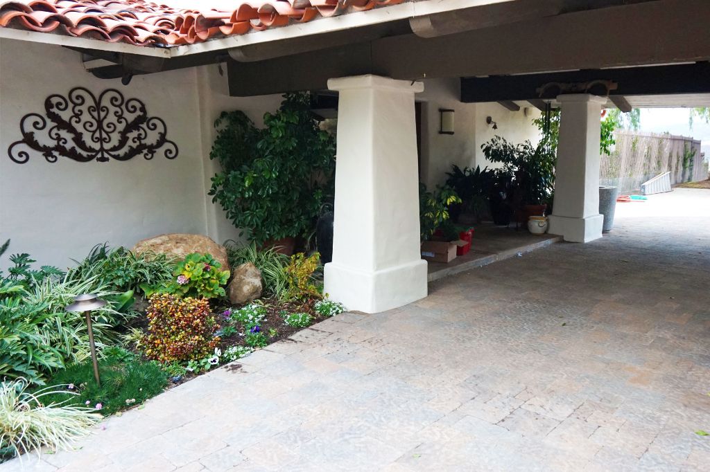Paver driveway running under a tile-roofed entry carried on custom concrete pillars