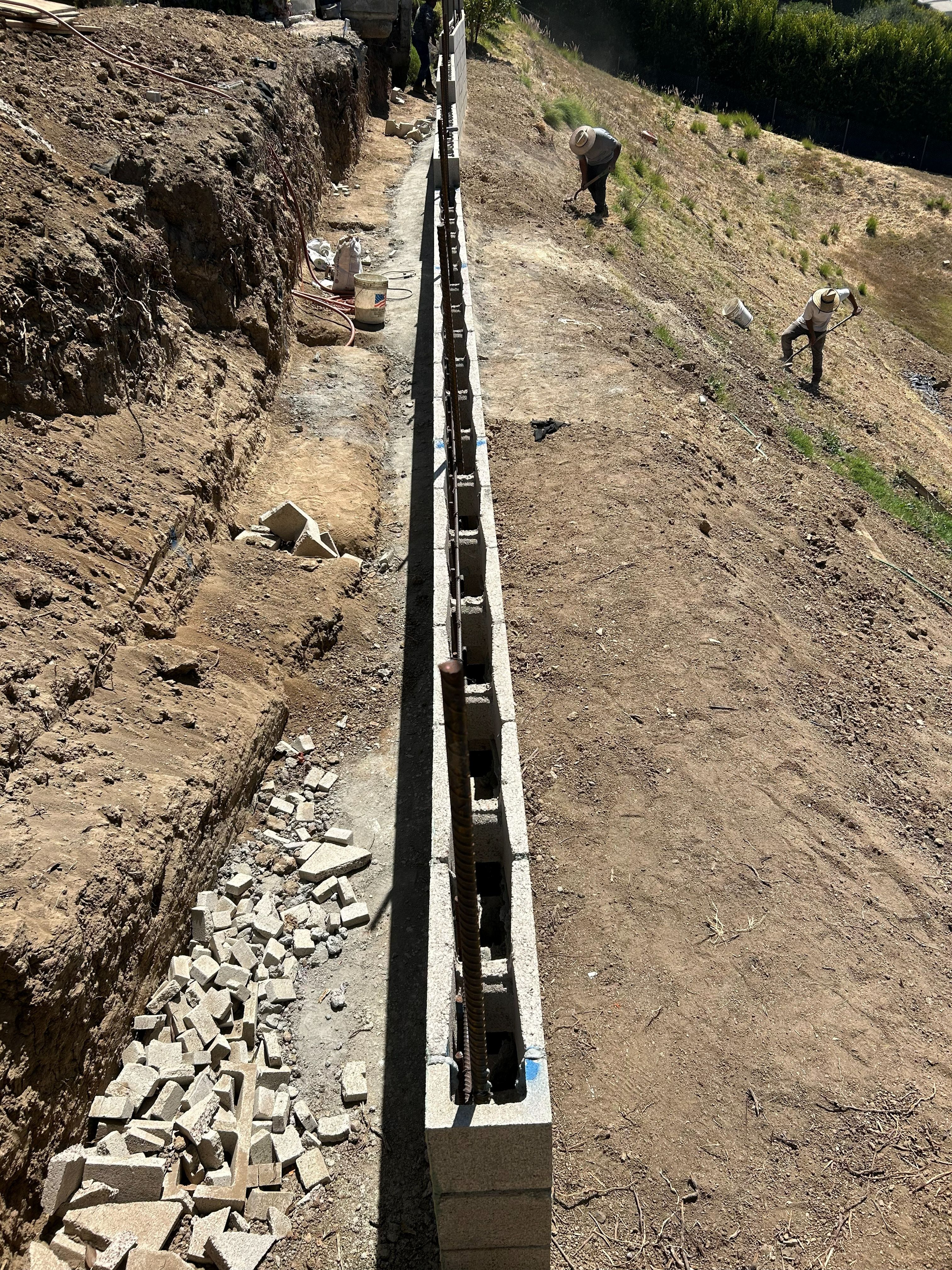 Reinforced retaining wall under construction, showing the footing, rebar and drainage course