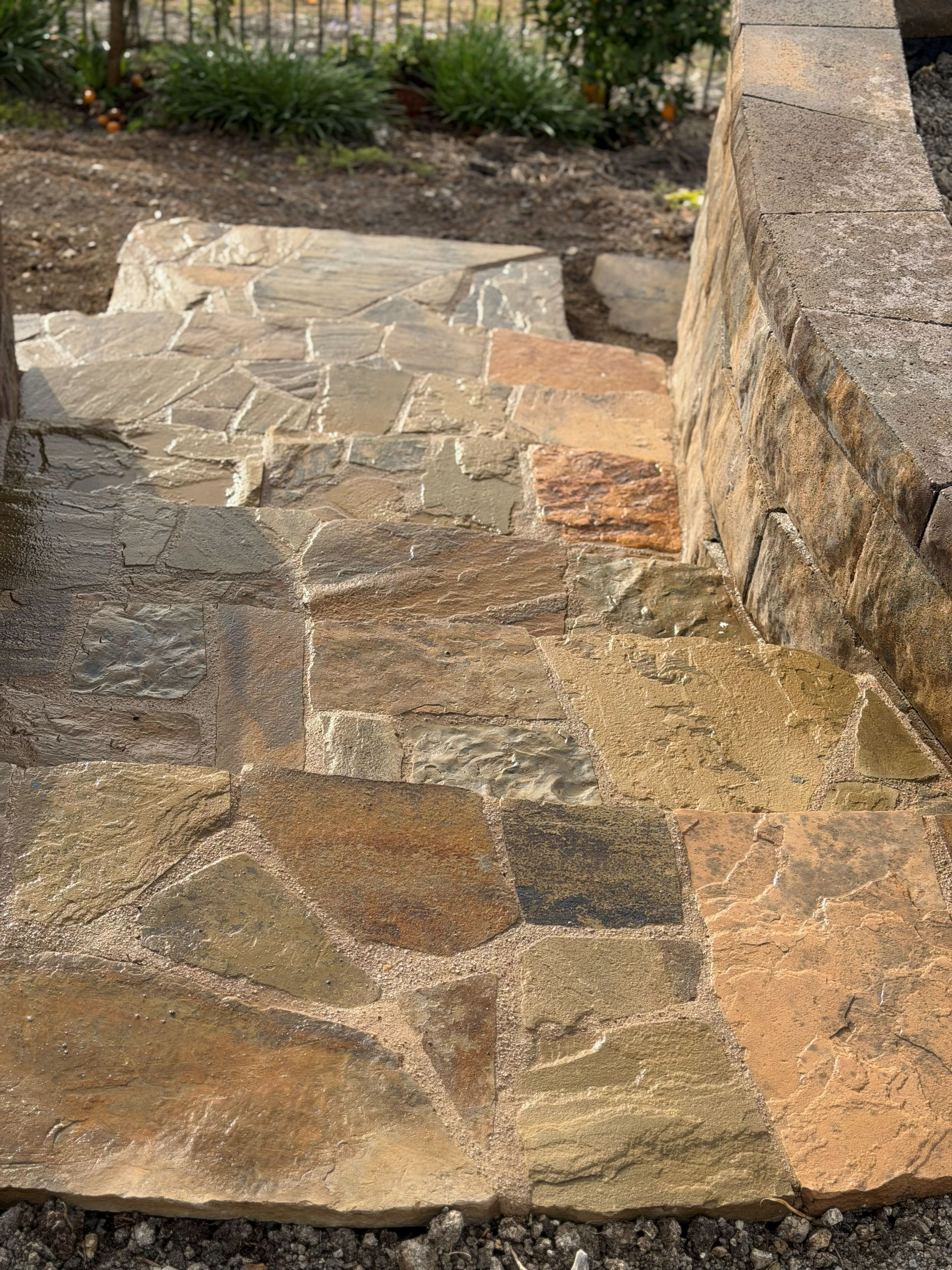 Sandstone landing and flagstone path meeting a stacked-stone wall