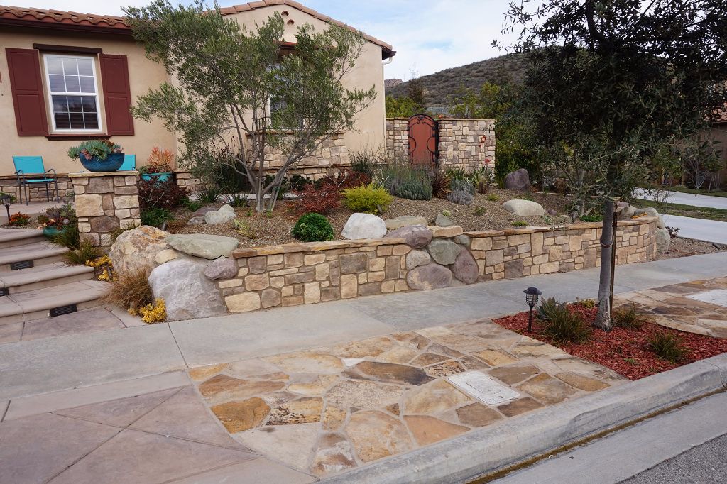Flagstone inset sidewalk with a boulder-set stone retaining wall running across the frontage