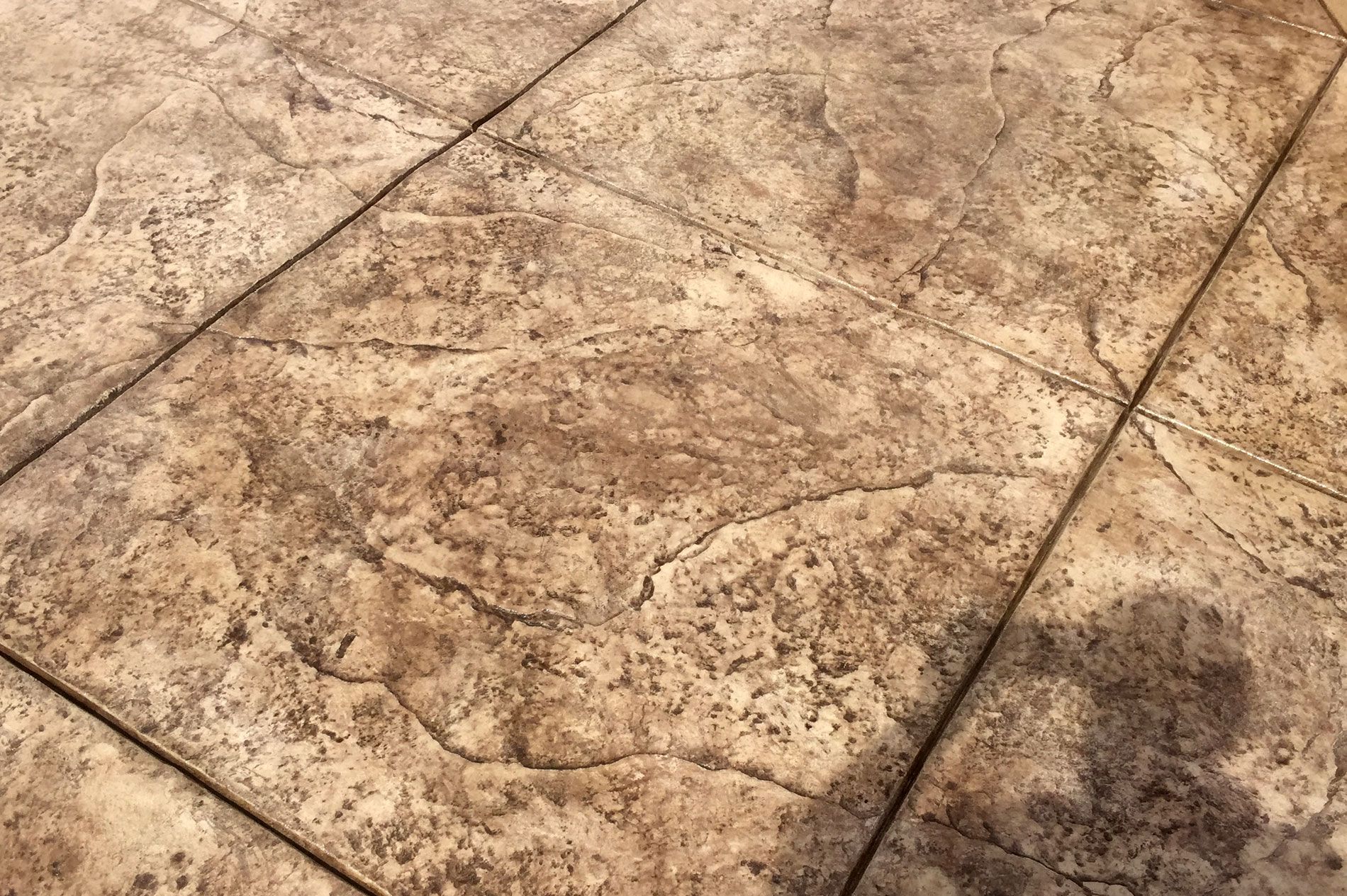 Large-format stamped concrete flatwork with saw-cut joints, the release color still damp from the pour