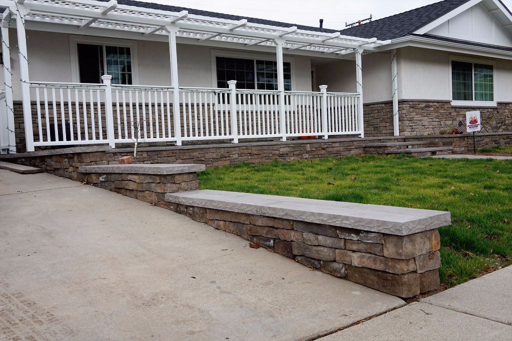 Low stone garden wall with a flat cut cap, edging the lawn in front of a ranch house