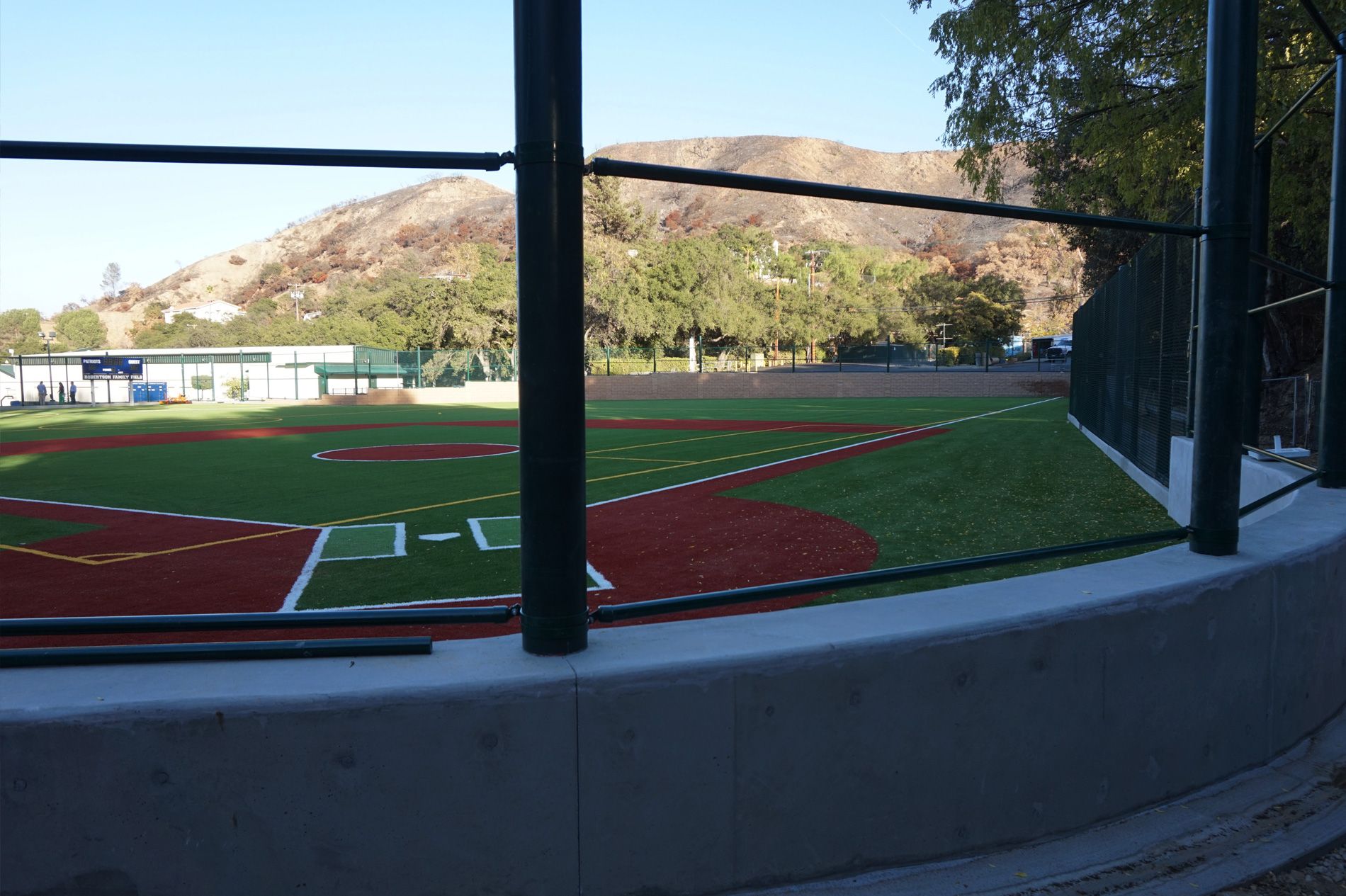 Backstop netting and rail on their poured concrete surround, looking out over the Viewpoint School diamond
