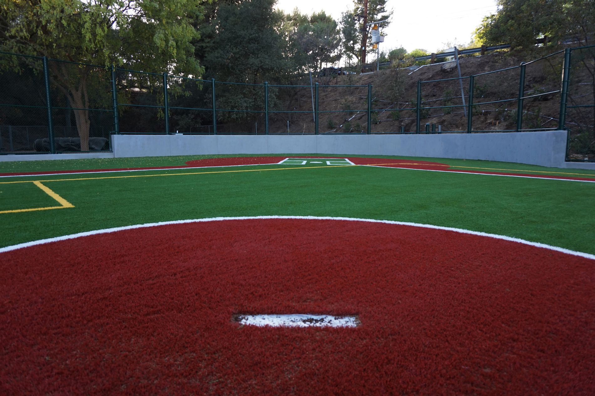 Infield turf meeting the red warning track at Viewpoint School, with the pitching rubber set in