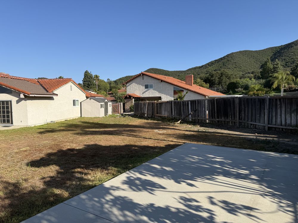 Leaning timber boundary fence behind a lawn, with a poured concrete slab already in place