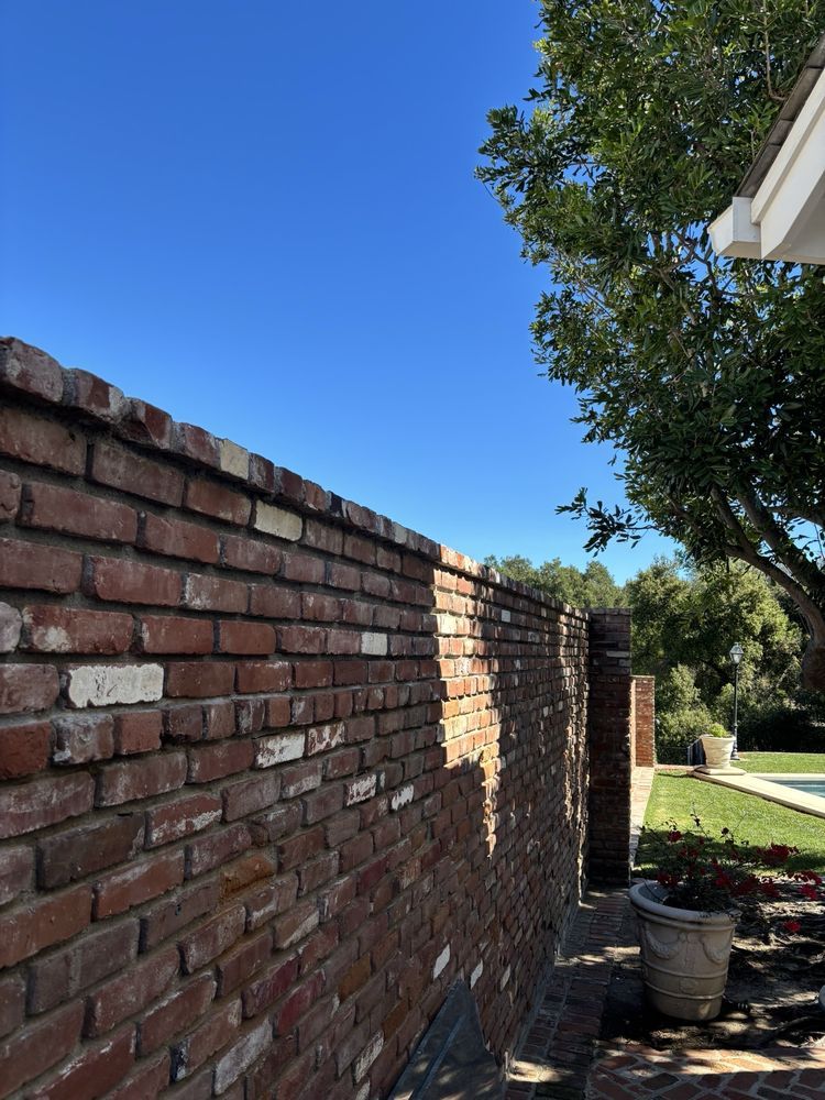Tall red brick garden wall with mature trees behind