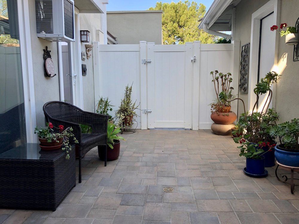 Entry courtyard with a white gate, potted plants and paver flooring