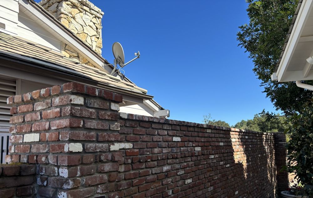 Red brick garden wall running alongside a tile-roofed house