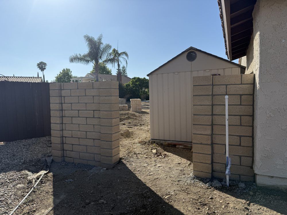 Block wall and shed standing on bare graded ground