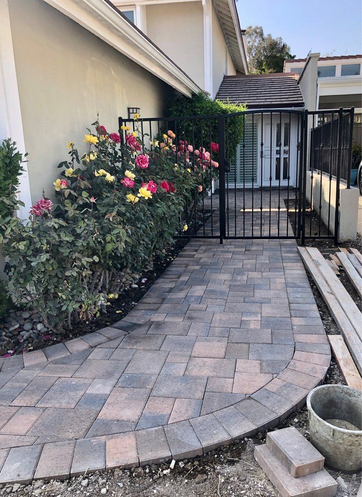 Curving paver walkway alongside rose beds leading to a side entry