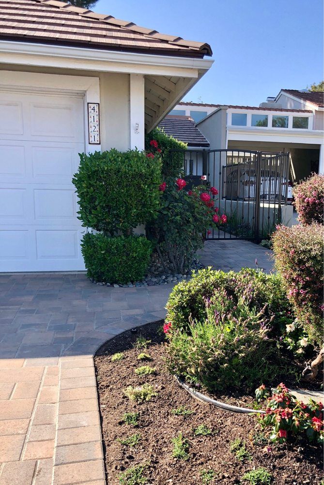Paver driveway with planted borders in front of a home