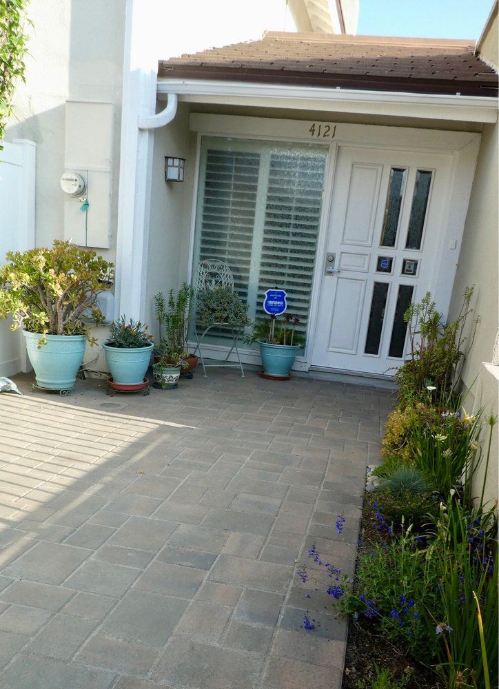 Home entry with potted plants set over paver flooring